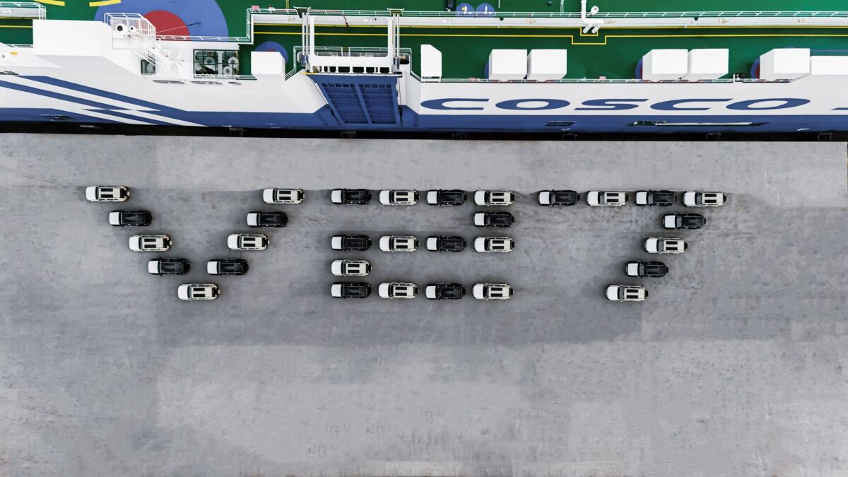 Вид сверху на судно COSCO с парком автомобилей на причале