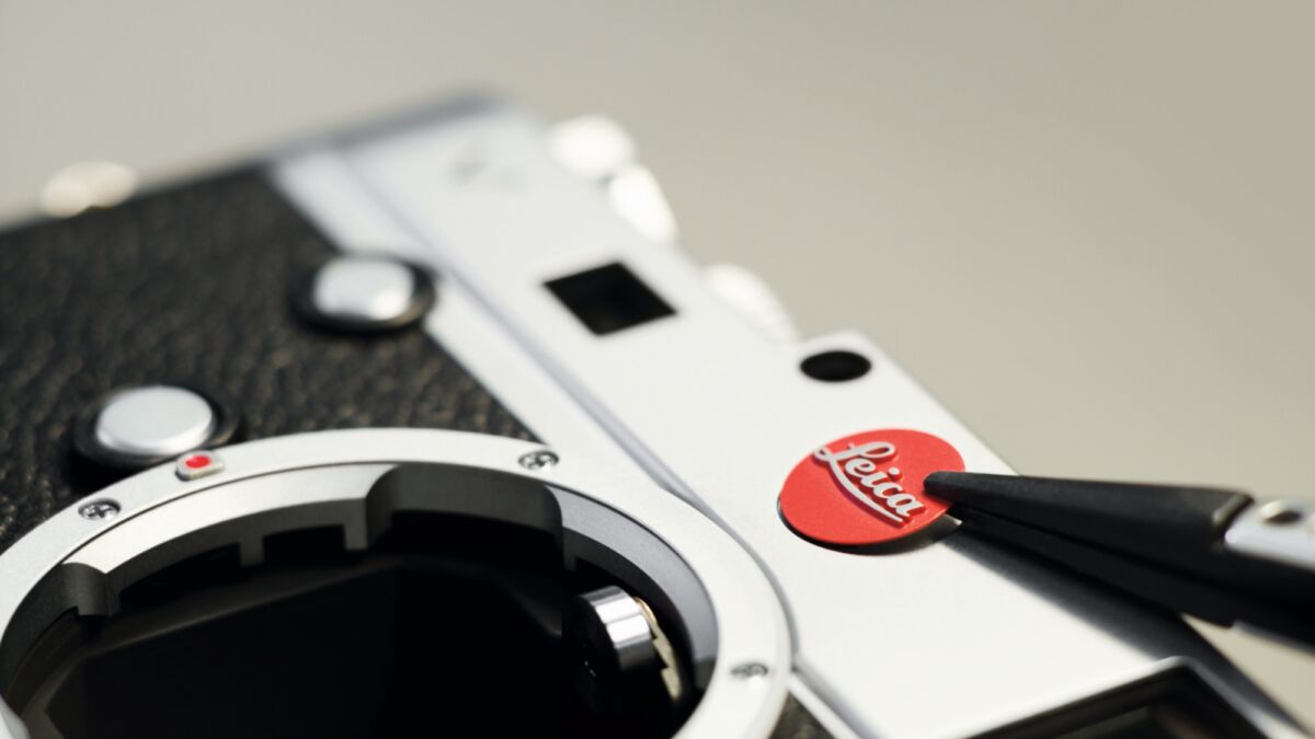Затвор камеры Leica крупным планом: белый и чёрный корпус, механическая деталь в обзоре дизайна