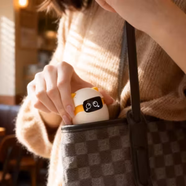 Женщина показывает карманный AI-питомец Takway Sweekar в виде игрушечного робота