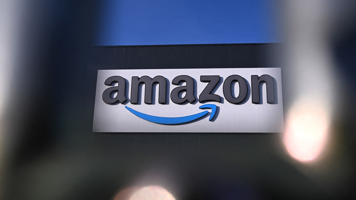 Знак Amazon на фасаде здания с логотипом и синей стрелкой на фоне дневного неба