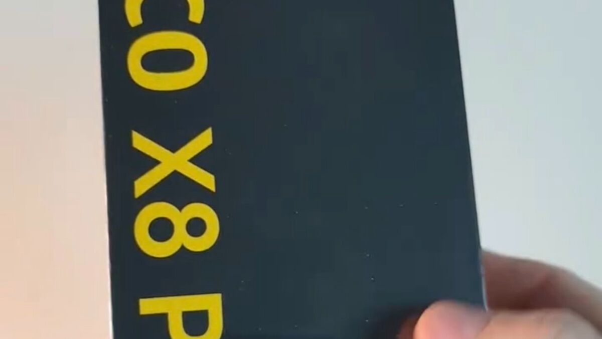 Рука держит коробку Poco X8 Pro 5G с черным фоном