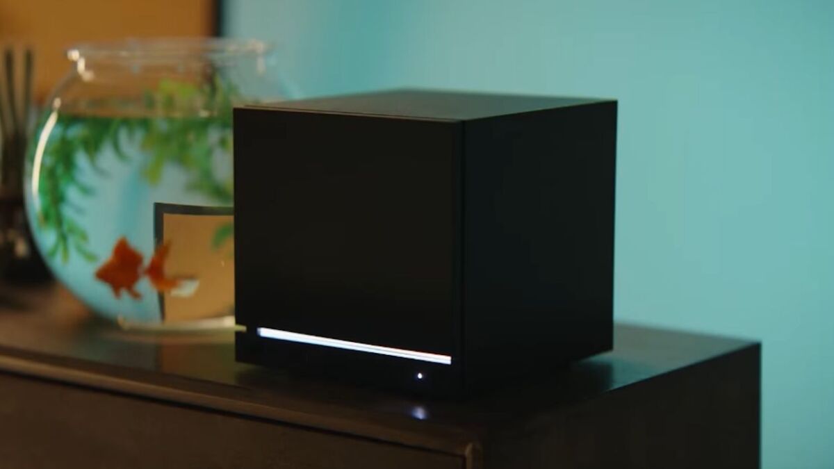 Steam Machine от Valve в черном кубическом корпусе на поверхности, рыбы в аквариуме на заднем плане