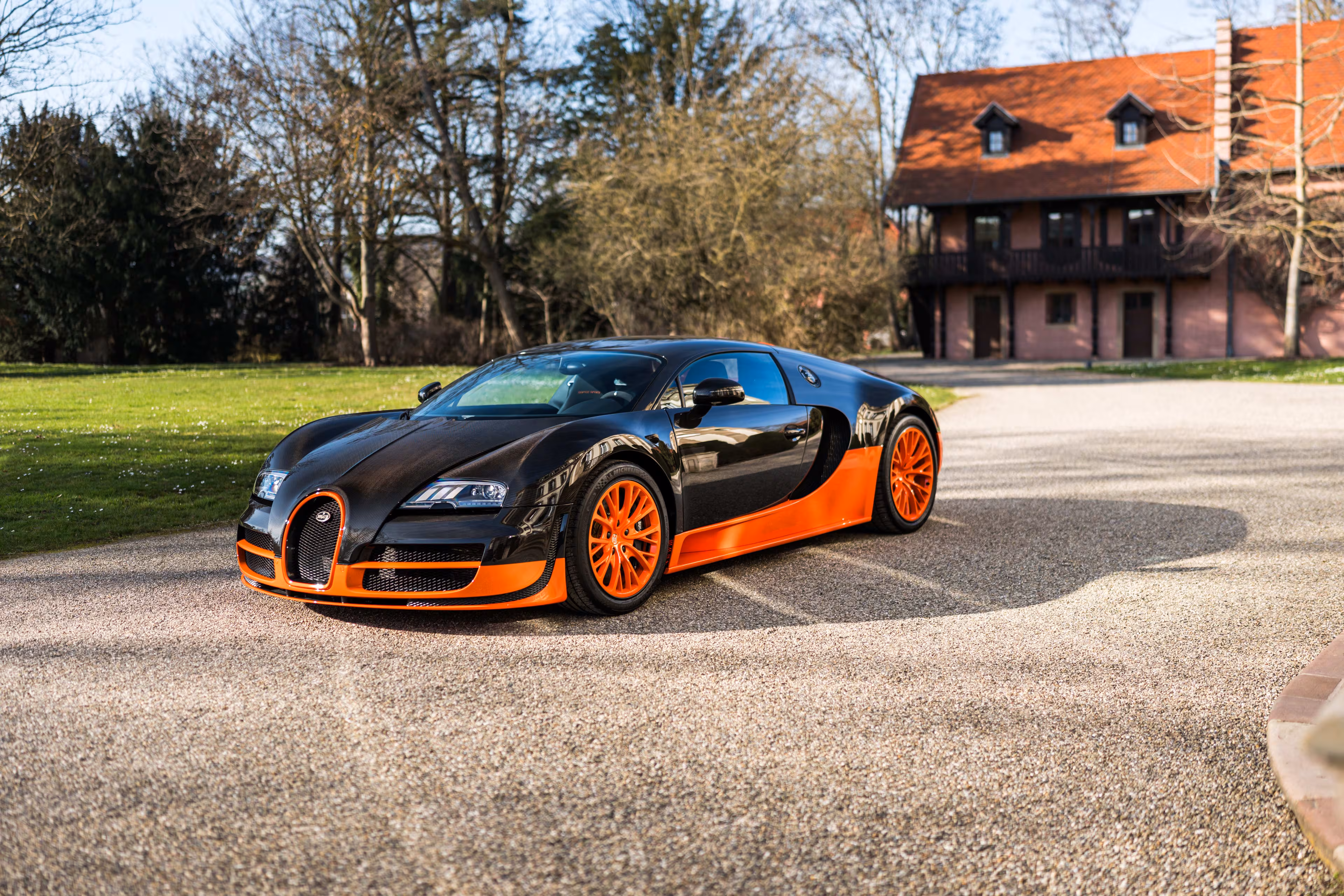 Черно-оранжевый Bugatti Veyron Super Sport на дороге
