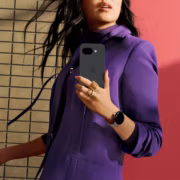Женщина в пурпурном костюме держит смартфон Google Pixel 7a