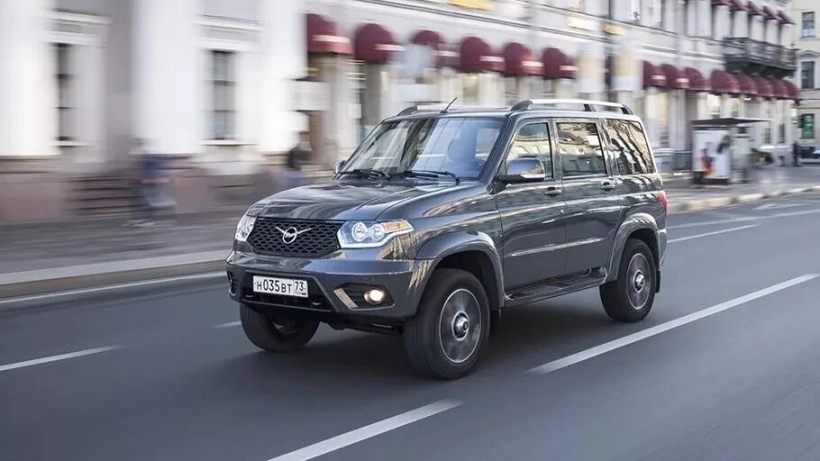 Роскошный черный внедорожник УАЗ Патриот движется по городской улице