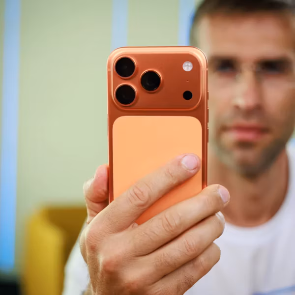 Пользователь держит iPhone 18 Pro с тремя камерами во время съемки селфи