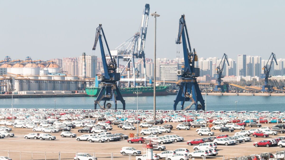 Порт с крупными кранами и стоянкой электрических автомобилей, подготовка к экспорту машин