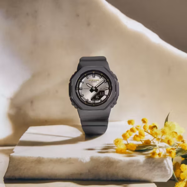 Черные часы Casio G-Shock на белом фоне с желтыми цветами к Международному женскому дню