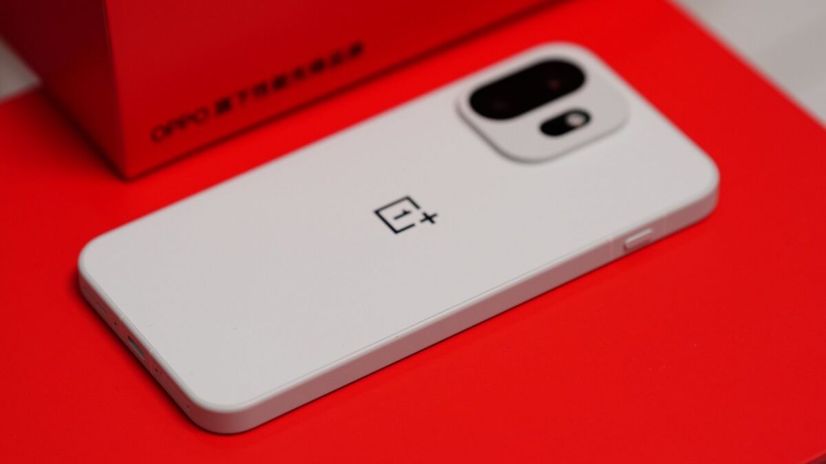 Белый смартфон OnePlus 15T на красной поверхности и коробке