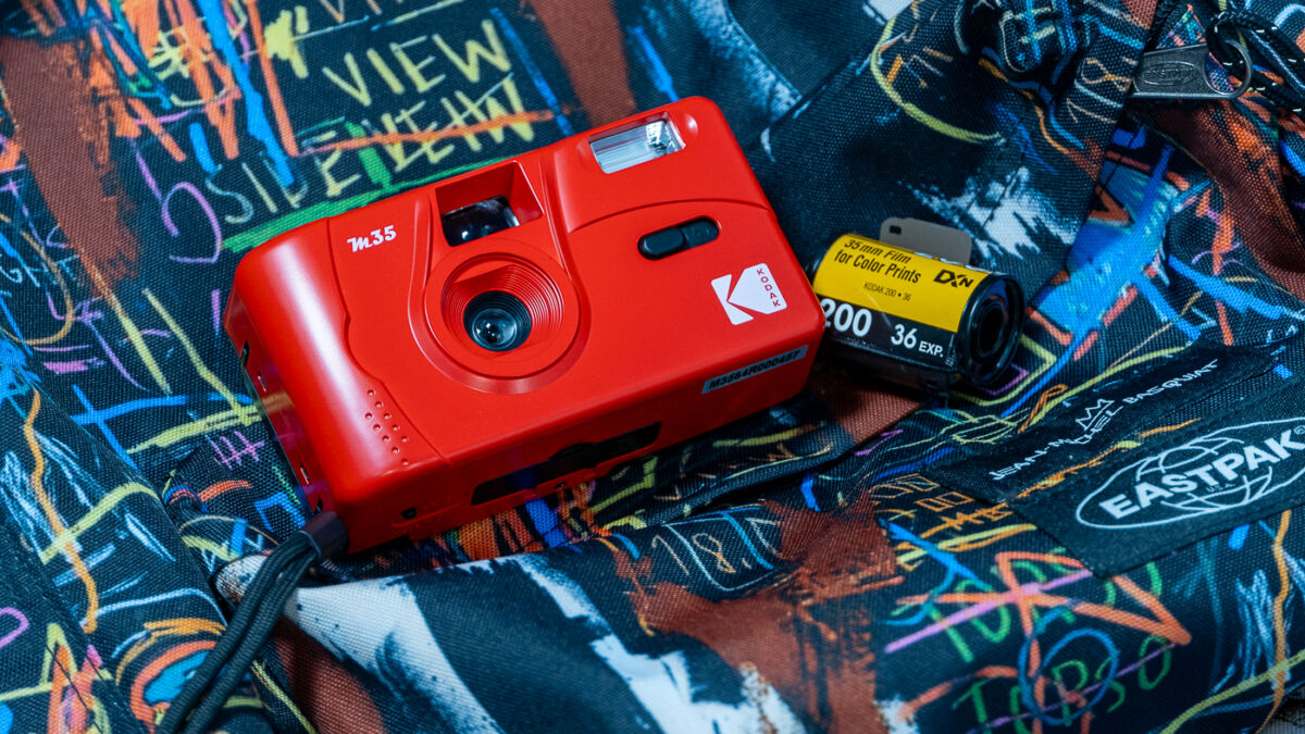 Красный пленочный фотоаппарат Kodak M35 на ярком рюкзаке
