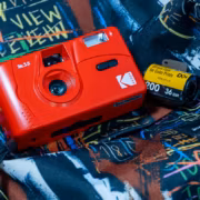 Красный пленочный фотоаппарат Kodak M35 на ярком рюкзаке