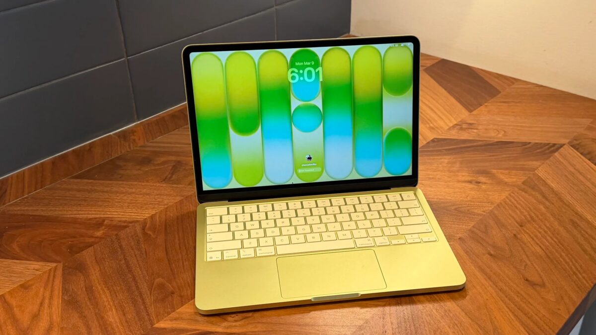 MacBook с зелёной подсветкой клавиатуры и экраном на фоне обновления macOS 26.4