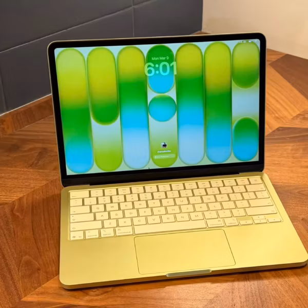 MacBook с зелёной подсветкой клавиатуры и экраном на фоне обновления macOS 26.4