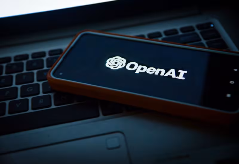 Смартфон с логотипом OpenAI на экране рядом с интерфейсом ChatGPT в США