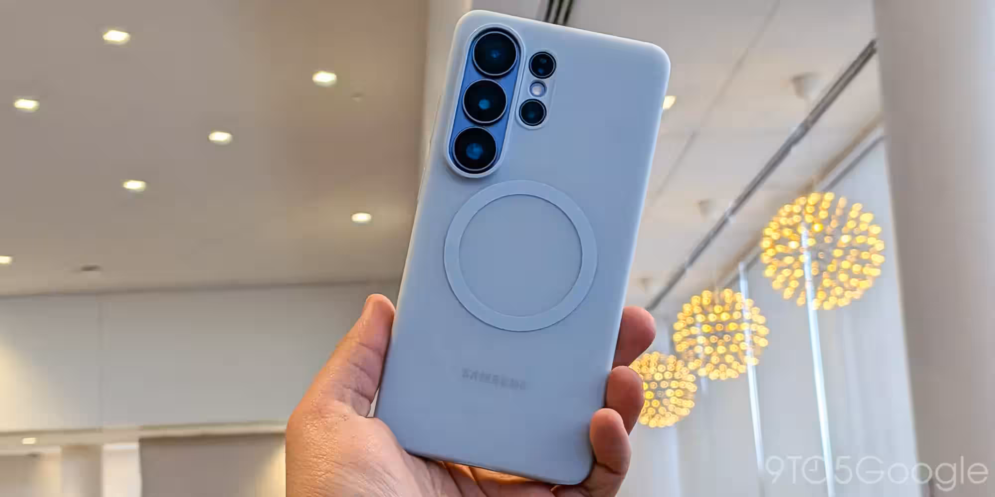 Рука держит белый Samsung Galaxy с чехлом на задней панели