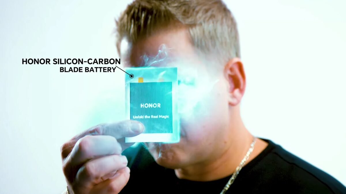 Человек держит прозрачную карточку с логотипом Honor и текстом Unlock the Real Magic