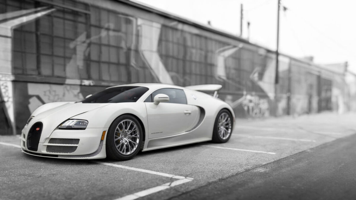 Белый спорткар Bugatti стоит на асфальте у стены в городской среде