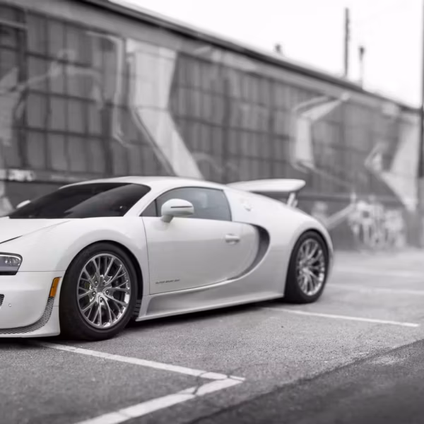 Белый спорткар Bugatti стоит на асфальте у стены в городской среде