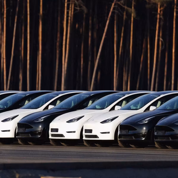 Белые и черные Tesla Model 3 в ряду на парковке