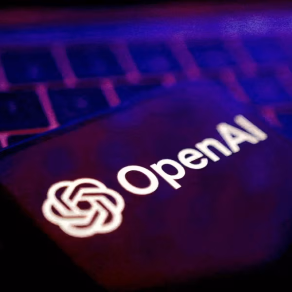 Логотип OpenAI на смартфоне в темной подсветке клавиатуры ноутбука
