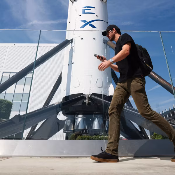 Человек в черной футболке идет мимо ракеты SpaceX