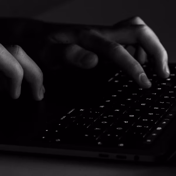 человек печатает на клавиатуре MacBook с подсветкой