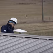 Человек в каске и наушниках с ноутбуком на крыше здания