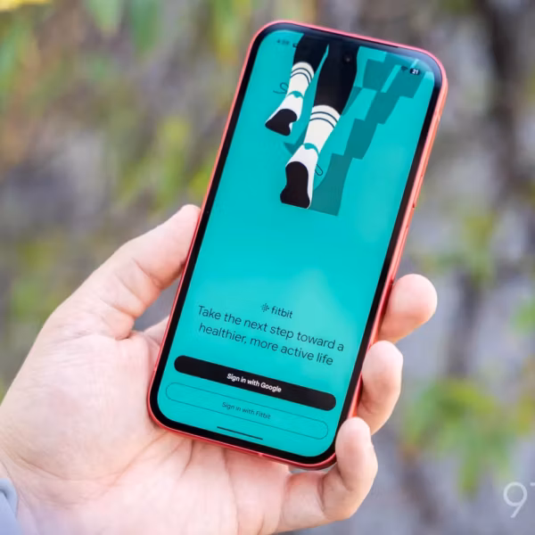Мужская рука держит смартфон Fitbit со стартовым экраном
