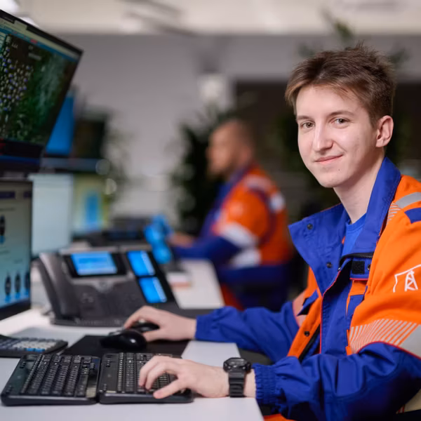 Молодой мужчина в форме Газпром нефти за компьютером создает ИИ-агента