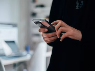 Человек держит смартфон МегаФон в руках в помещении