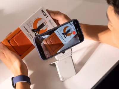 Человек с смартфоном снимает трекер и кошелёк Moft