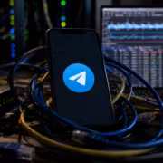 Модель смартфона с логотипом Telegram подключена к кабелям и сетевым устройствам