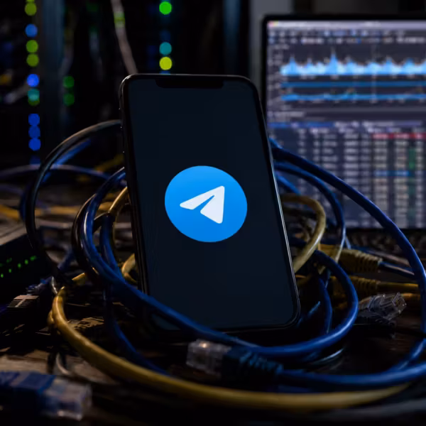 Модель смартфона с логотипом Telegram подключена к кабелям и сетевым устройствам
