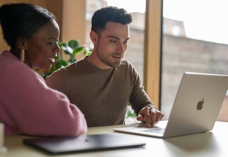 Двое людей работают за ноутбуком Apple MacBook