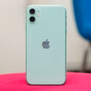 Зеленый iPhone 11 на розовой ткани сзади
