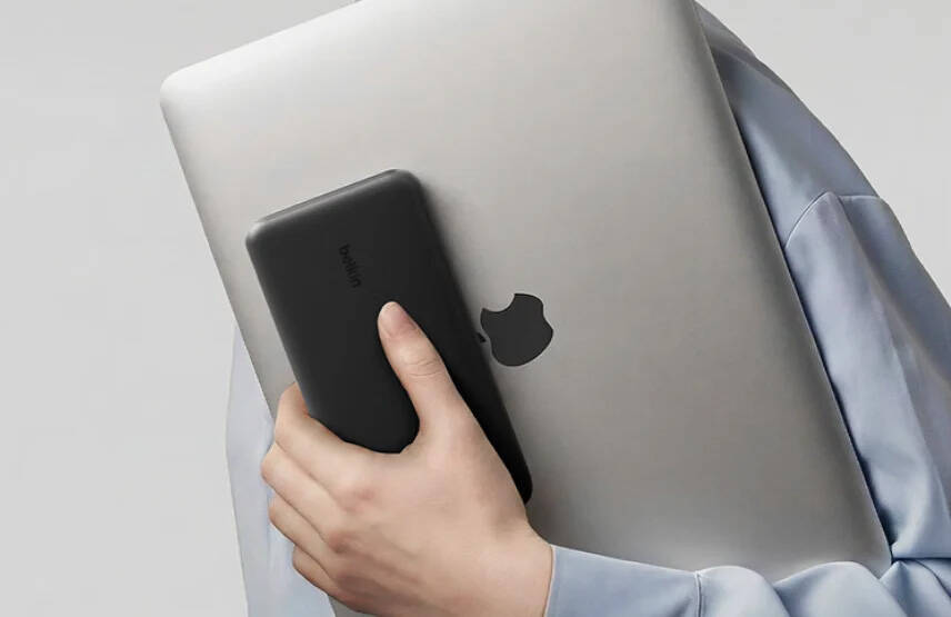 Человек держит powerbank Belkin UltraCharge Pro 25K и MacBook