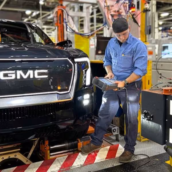 Работник на заводе GM с роботом для сборки автомобиля GM