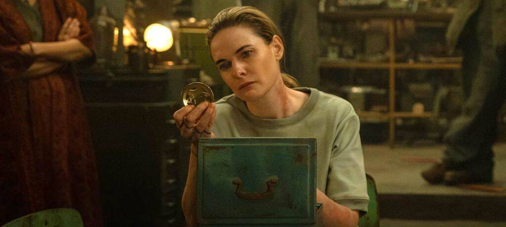 Женщина в серой футболке держит медаль и книгу сериал Silo