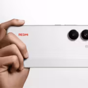 Ручка держащая белый смартфон Redmi Turbo 5 с двумя камерами