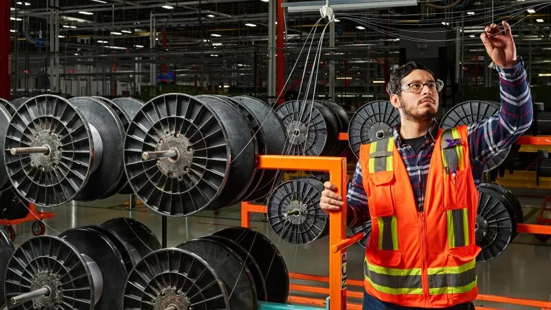 Рабочий в жилете у катушек оптоволоконного кабеля Corning