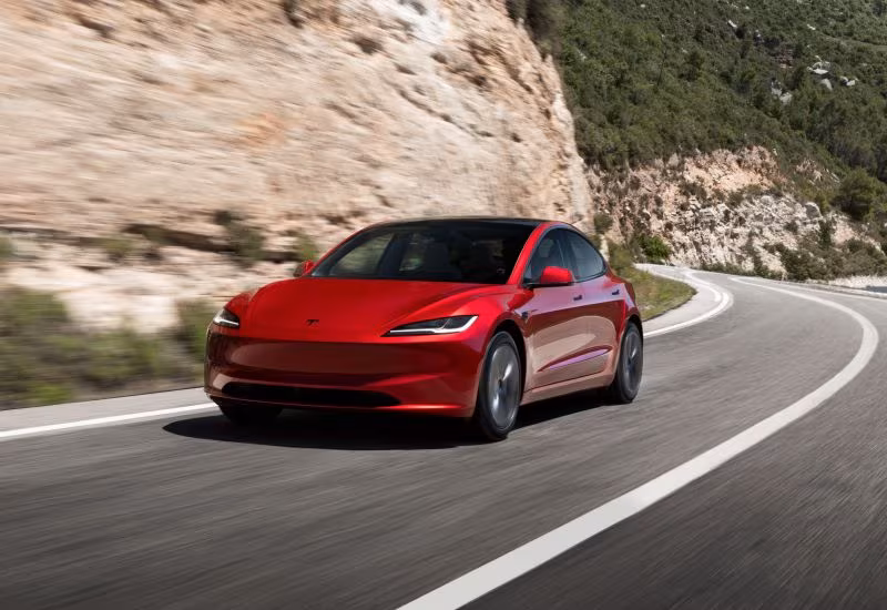 красный Tesla Model 3 на горной дороге