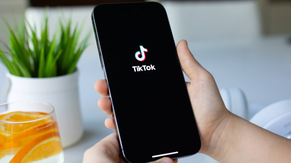 Мужчина держит iPhone с логотипом TikTok в руке
