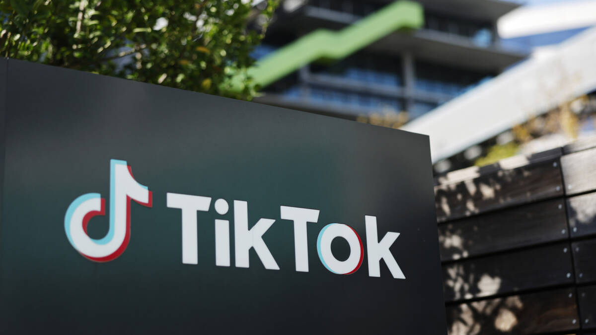 Стенд с логотипом TikTok рядом с деревьями и зданием