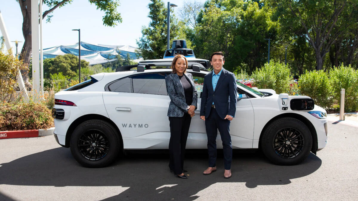 Двое человек возле автомобиля Waymo беспилотное такси