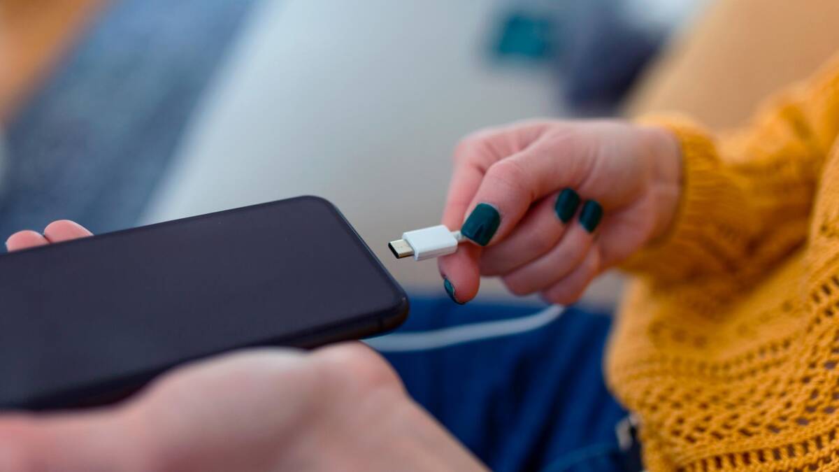 Почему не стоит постоянно держать смартфон в режиме энергосбережения 1 Человек вставляет USB-C кабель в смартфон,